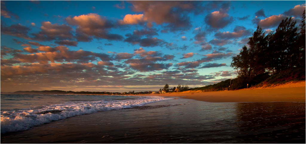 Praia da Ponta do Ouro ao amanhecer, com nuvens alaranjadas sobre o mar